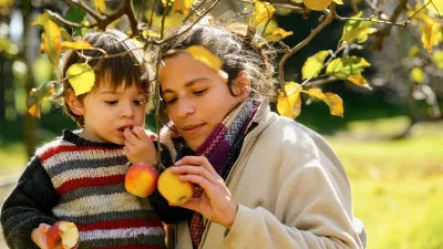 乌拉圭圣何塞市农村地区，2岁的约金（Joaquín）在家中帮助母亲罗西娜摘苹果。